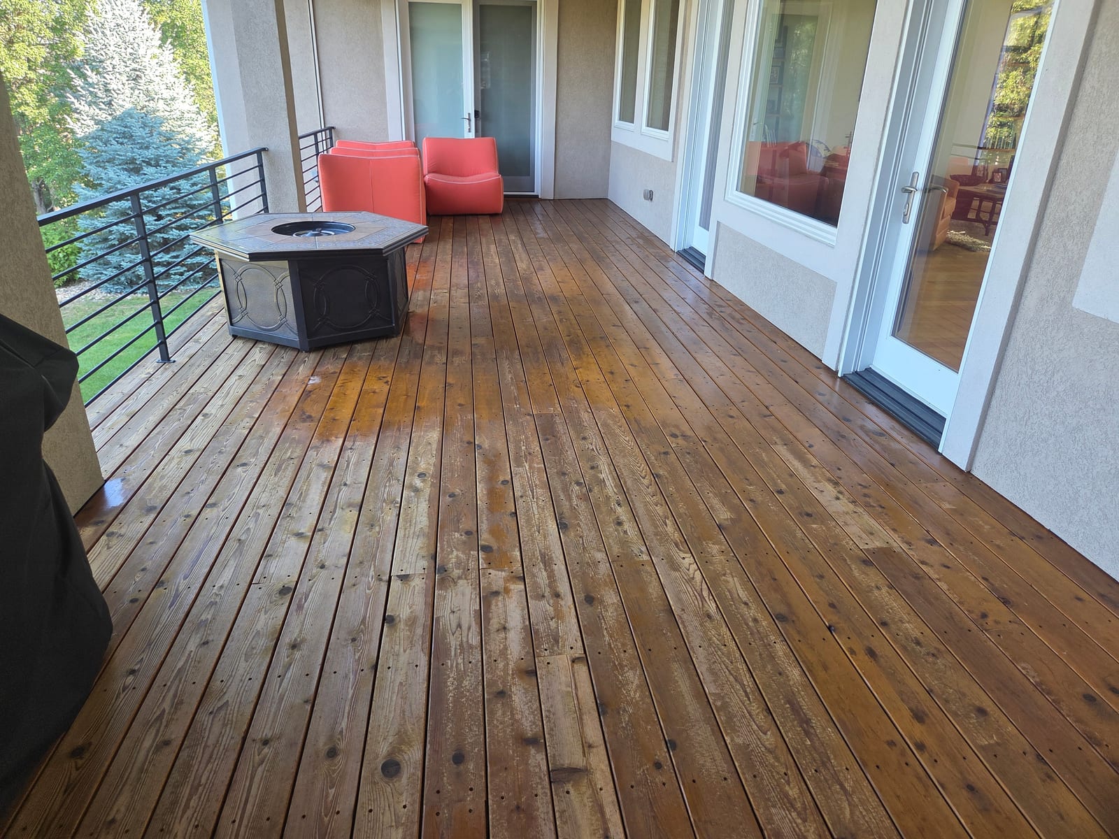 Wide shot of the deck before refinishing, showing uneven, patchy old stain across the boards