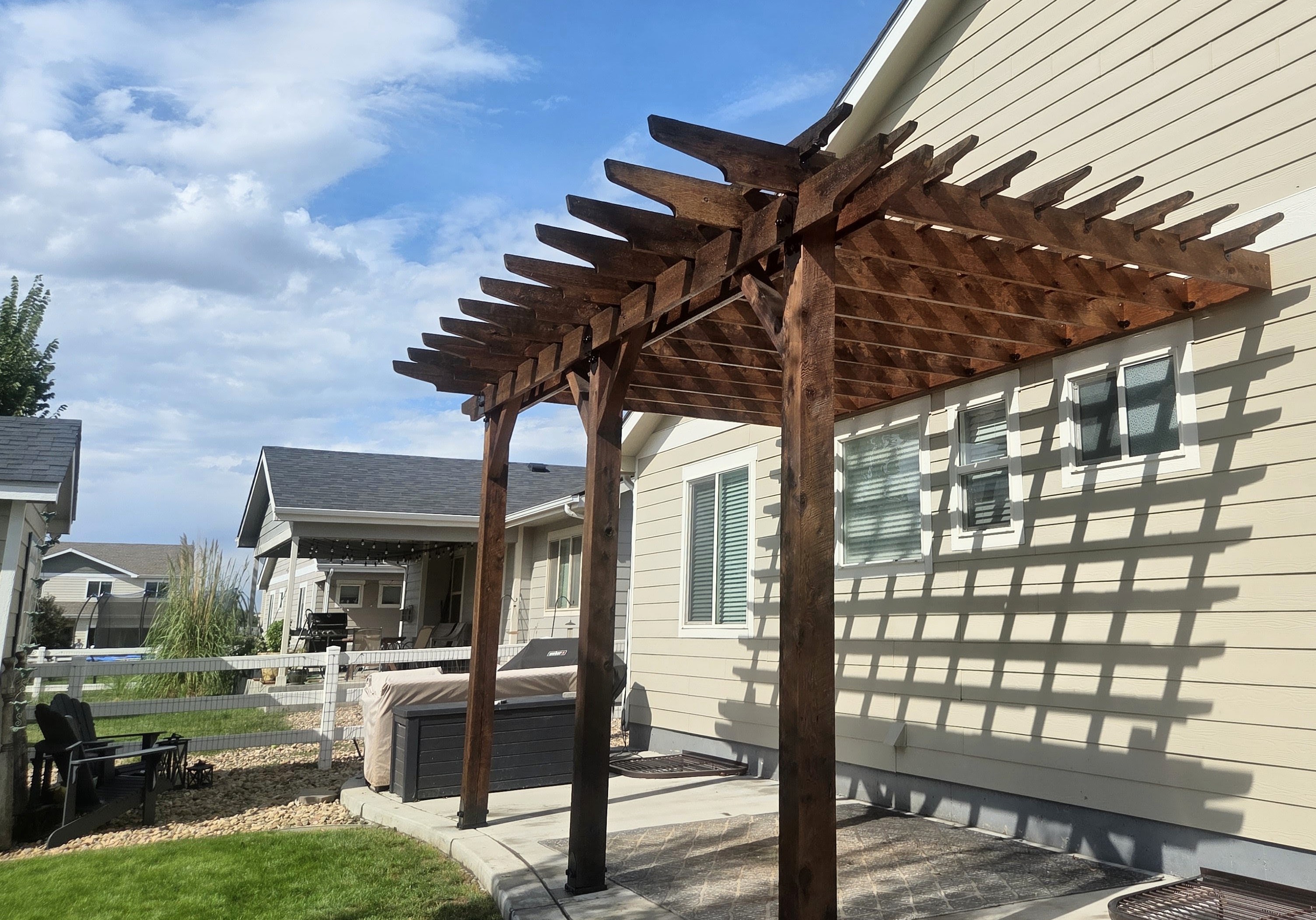 Cedar pergola stained dark brown attached to the back of a Colorado home